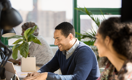 Image of a man in an office working on a laptop.