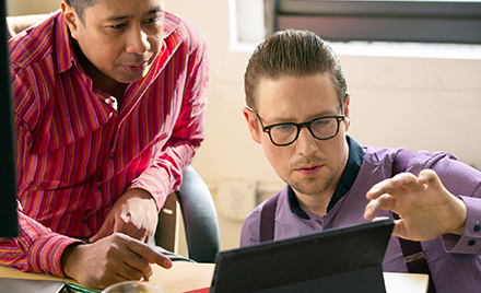 Two co-workers collaborating on a project on a laptop PC.