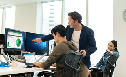 Image of two workers collaborating at a PC.