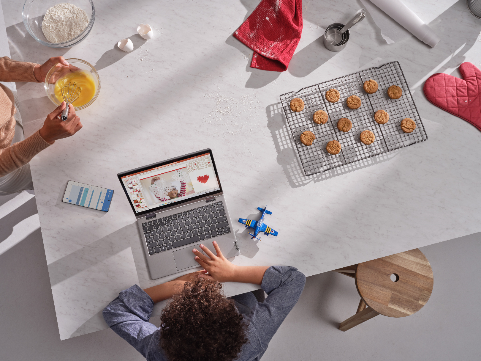 Family hanging out at home baking holiday cookies using Lenovo Ideapad Flex 3 to make holiday cards
