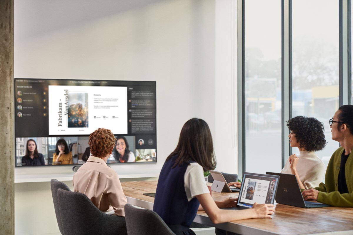 Remote attendees participating in a Microsoft Teams Room (MTR) meeting while people in a conference room are viewing PowerPoint content on the front of room (FoR) screen displaying remote participants in Front Row.