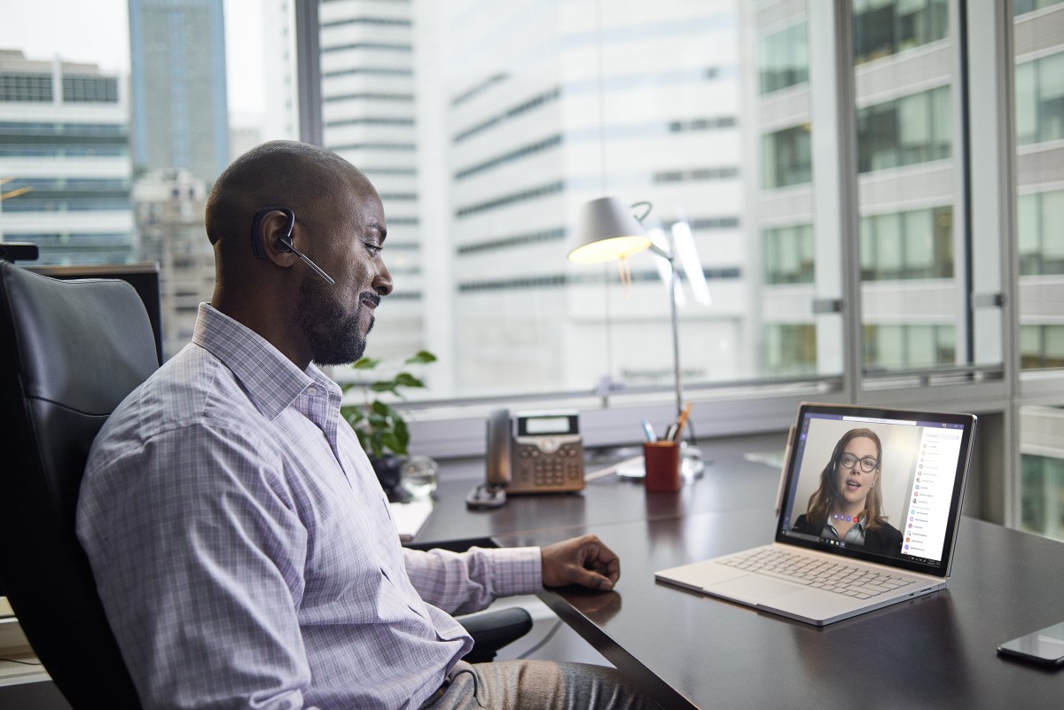 Business executive working on a Surface Pro Book at desk, running Microsoft Teams.