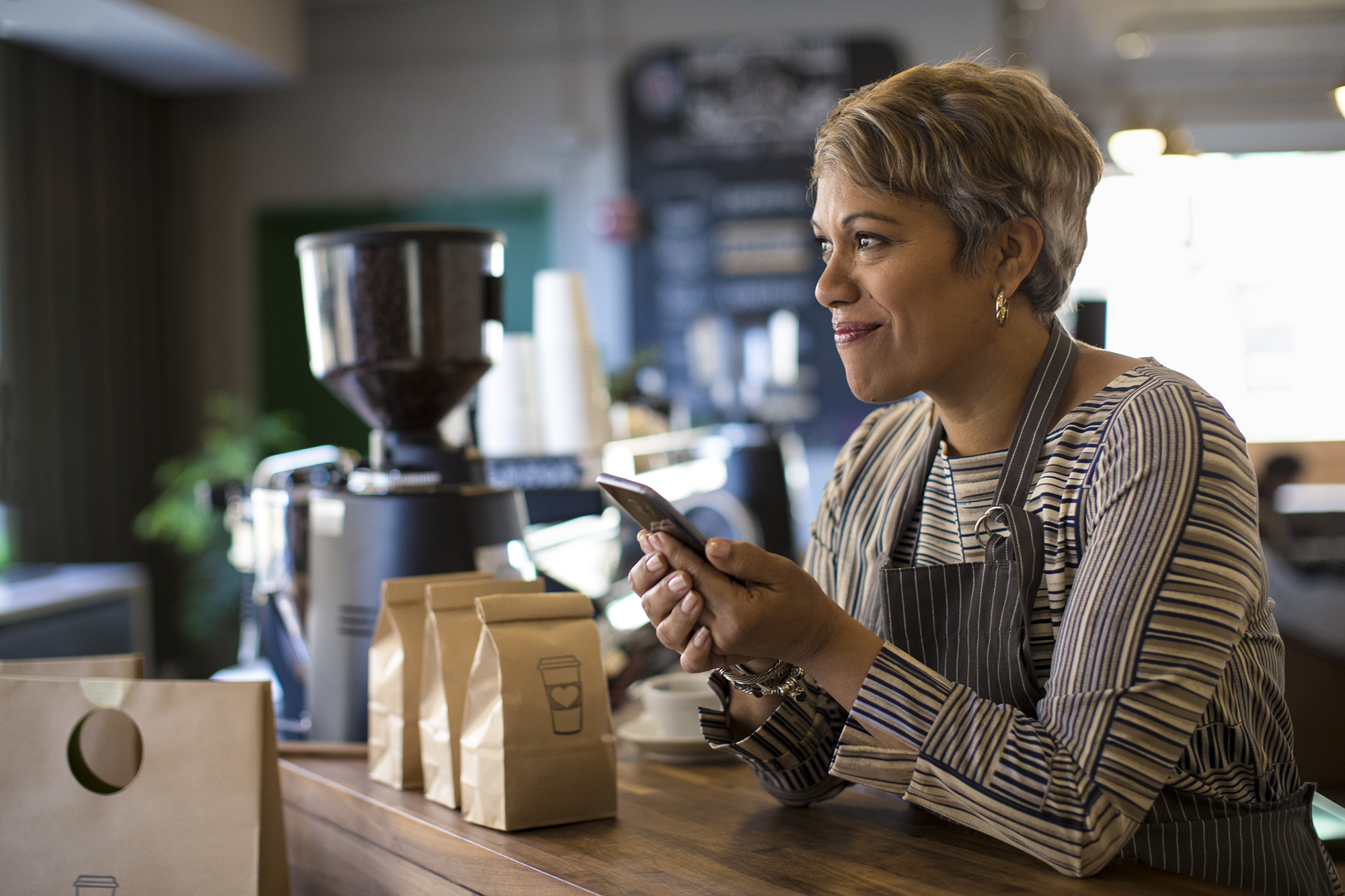 Barista behind counter using mobile device. 