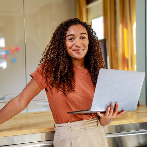 Smiling female entrepreneur with laptop standing in office.