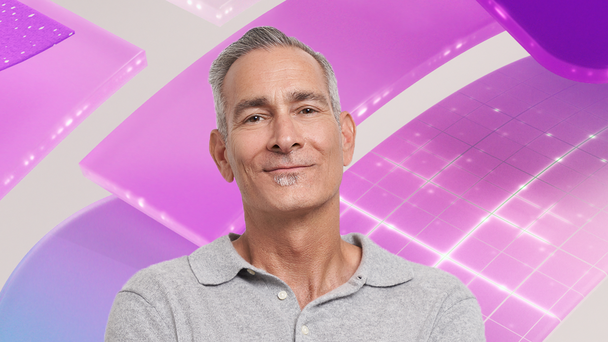A man smiling for a picture in front of a purple geometric design background